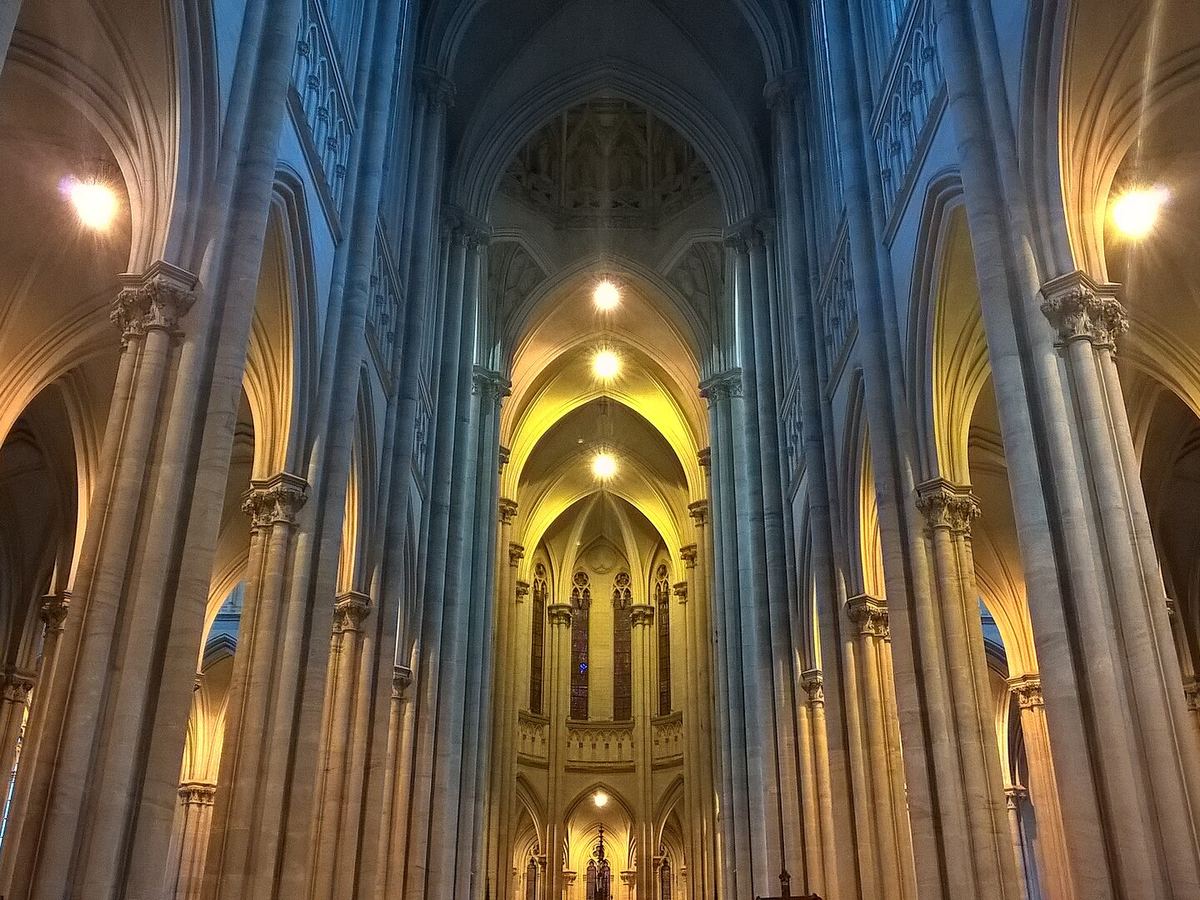 The vaulted nave of a Gothic cathedral lit for evening